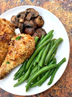 a white plate topped with chicken, green beans and mushrooms