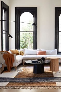 a living room filled with lots of furniture next to two large black windowed windows