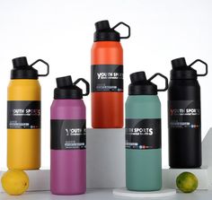 thermos bottles are lined up next to lemons and an orange on a white surface