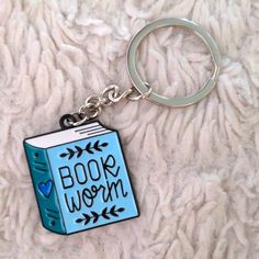 a book worm keychain is sitting on a blanket