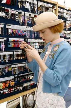 a woman looking at her cell phone in front of a display of earring necklaces