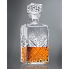 an empty glass decanter with a diamond pattern on the top and bottom, sitting on a reflective surface