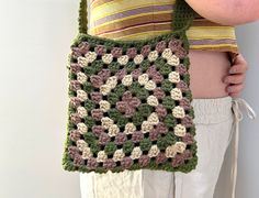 a woman is holding a crocheted bag in front of her stomach and wearing white pants