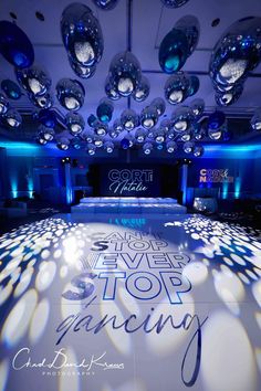 the dance floor is decorated with blue lights and disco ball chandeliers for an event