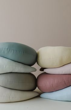 four pillows stacked on top of each other in different colors and sizes, one is pink, the other is blue