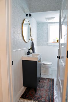 a bathroom with a sink, toilet and rug on the floor in front of it