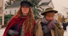 two women in hats and scarves walking down the street