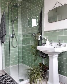 a bathroom with green tiles and a white pedestal sink next to a walk in shower