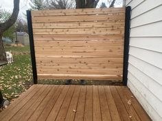 a wooden deck with a black gate on the side and a white dog standing next to it