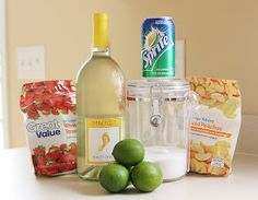 limes, chips, and bottles of wine on a counter top next to snacks