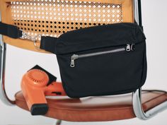 a black fanny bag sitting on top of a chair next to an orange blower