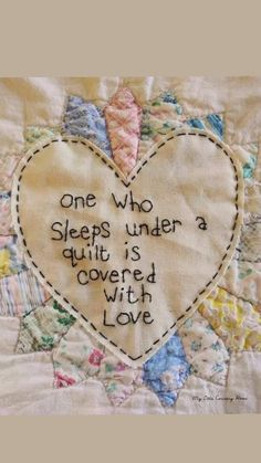 a quilted heart with the words one who sleeps under a quilt is covered with love