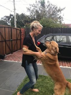 a woman is playing with her dog outside