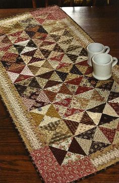 a quilted table runner with two cups on it