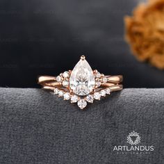 an engagement ring with a pear shaped diamond surrounded by smaller round brilliant cut diamonds in rose gold