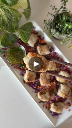 a white plate topped with meatballs and veggies next to a potted plant