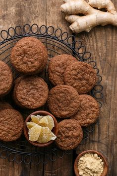 some cookies are sitting on a plate next to two bowls with ginger flakes in them