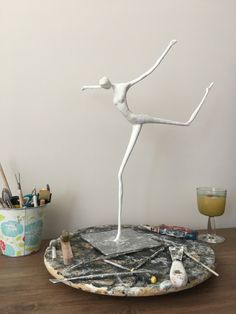 a white statue is standing on top of a table next to some paint and brushes