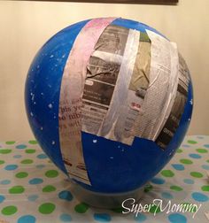 a large blue ball covered in newspaper sitting on top of a polka dot table cloth