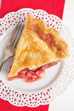 a piece of pie on a white plate with a fork and red napkin behind it