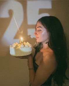 a woman holding a cake with candles in her hand and the number twenty five on it