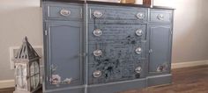 a blue cabinet with lots of writing on the doors and drawers, next to a clock