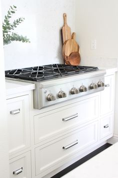 a stove top oven sitting inside of a kitchen next to white cupboards and drawers