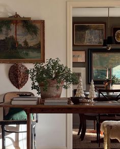 a dining room table with plants and pictures on the wall