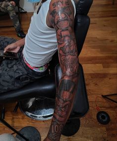 a man with tattoos on his arm sitting in a chair