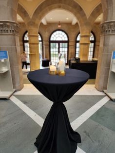 a black table with two candles on it in front of an arched doorway and windows