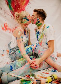 a man and woman sitting next to each other covered in paint