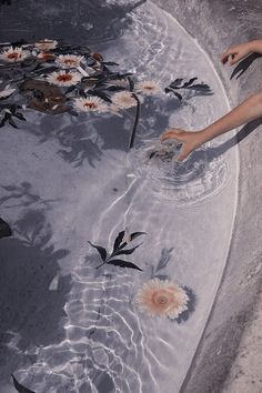 someone reaching for flowers in the water with their hands and feet above the water's surface