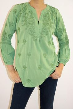 Immerse yourself in the charm of the Cassie Blouse, crafted from pure cotton in a mesmerizing array of variegated hues. Hand-embroidered with vintage chikankari in self, this blouse boasts an artful elegance. With a split open neckline and raglan sleeves featuring extended shirred extensions, it offers a timeless silhouette. The rounded hem adds a gentle touch, making it perfect to pair with your favorite jeans or skirt for an effortlessly chic look. Length: 27-29 inches. Sizes -  S - fits bust 34 M - fits bust 36 L - fits bust 38 XL - fits bust 40 0X - fits bust 42 Prewashed. Preshrunk. Wash Independantly in cold water. Line Dry. Light iron for best results. Green Embroidered Relaxed Fit Blouse, Spring Green Cotton Tunic, Green Blouse With Floral Embroidery And Relaxed Fit, Spring Green Blouse With Intricate Embroidery, Green Embroidered Blouse With Relaxed Fit, Spring Green Tunic With Chikankari Embroidery, Bohemian V-neck Embroidered Top With Chikankari, Bohemian V-neck Chikankari Embroidered Top, Bohemian Embroidered Top With Chikankari And V-neck