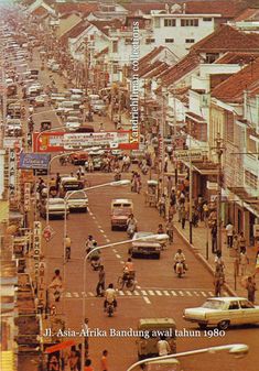 an old photo of people riding bikes and cars on the street in front of buildings