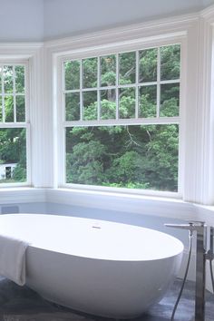 a large white bath tub sitting next to two windows