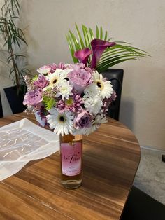 a vase filled with purple and white flowers on top of a wooden table next to a lace doily