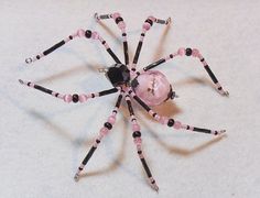 a pink and black beaded spider sitting on top of a table