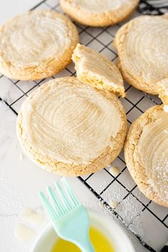 cookies with peanut butter frosting on a cooling rack next to a bowl of oil