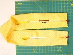 two pieces of yellow fabric sitting on top of a cutting board next to a ruler