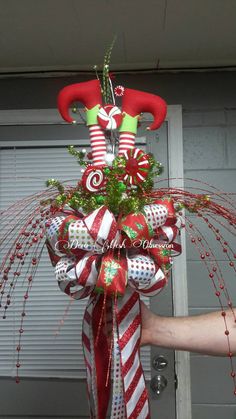 a christmas wreath with candy canes and elf hats on it, hanging in front of a garage door