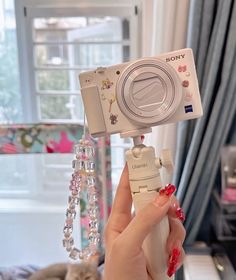 a person holding up a camera in front of a mirror with beads hanging from it