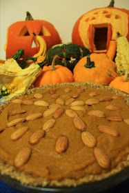 there is a pie with almonds on it and pumpkins in the back ground