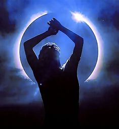 a woman standing in front of a blue moon with her hands up to her head