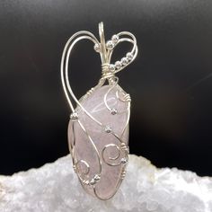 This beautiful rose quartz stone is a soft pink color with an iridescent glow coming from within the specimen. The stone is semi-transparent, so the internal crystalline structure is visible. The cool tone of the soft pink color is accented with silver plated anti-tarnish wire and beads. The graceful design of the wrapping brings out the beauty of the stone.  Ancient customs and lore indicate that gemstones can bring peace, health, protection and spiritual favor. There is a belief that rose quartz has calming effects and helps people develop strong friendships.  It is considered a stone representing love and compassion.    The pendant measures 3 inches high by 1 inch wide by 3/4 inch front to back.  The bale opening measures 1/3 inches high by 1/2 inches wide.    A complimentary faux suede Elegant Pink Jewelry Hand Wrapped, Elegant Hand Wrapped Pink Jewelry, Elegant Pink Hand Wrapped Jewelry, Elegant Hand Wrapped Rose Quartz Jewelry, Pink Rose Quartz Hand Wrapped Jewelry, Hand Wrapped Rose Quartz Pink Jewelry, Pink Rose Quartz Jewelry With Stones, Hand Wrapped Pink Rose Quartz Jewelry, Pink Rose Quartz Wire Wrapped Jewelry