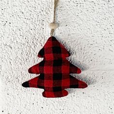 a red and black plaid christmas tree ornament hanging from a rope on a white wall