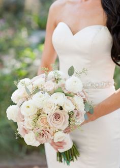 a bride holding a bouquet of white and pink flowers