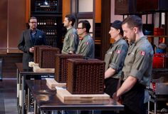 the men are standing in front of some wooden boxes and looking at something behind them