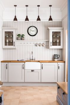 a kitchen with white cabinets and a clock on the wall next to it's cupboards