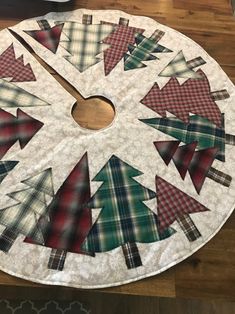 a clock made out of plaid fabric on top of a wooden table with christmas trees