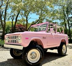 an old pink truck parked in front of some trees